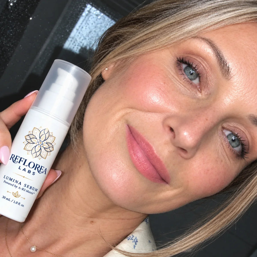 A woman over 40 holding Lumina Serum by her cheek