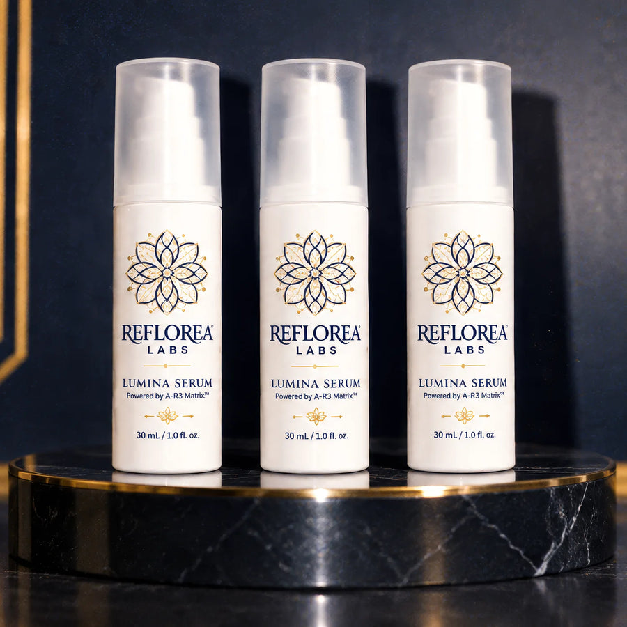 Three bottles of Lumina Serum on a marble stand