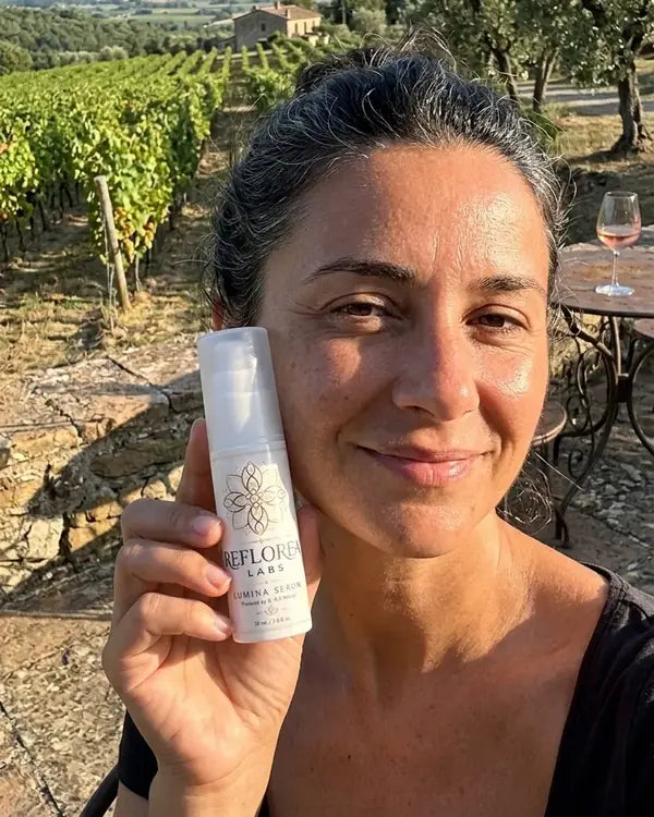A woman over 40 holding a bottle of Lumina Serum