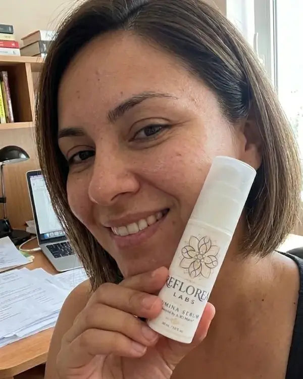 A woman over 40 holding a bottle of Lumina Serum