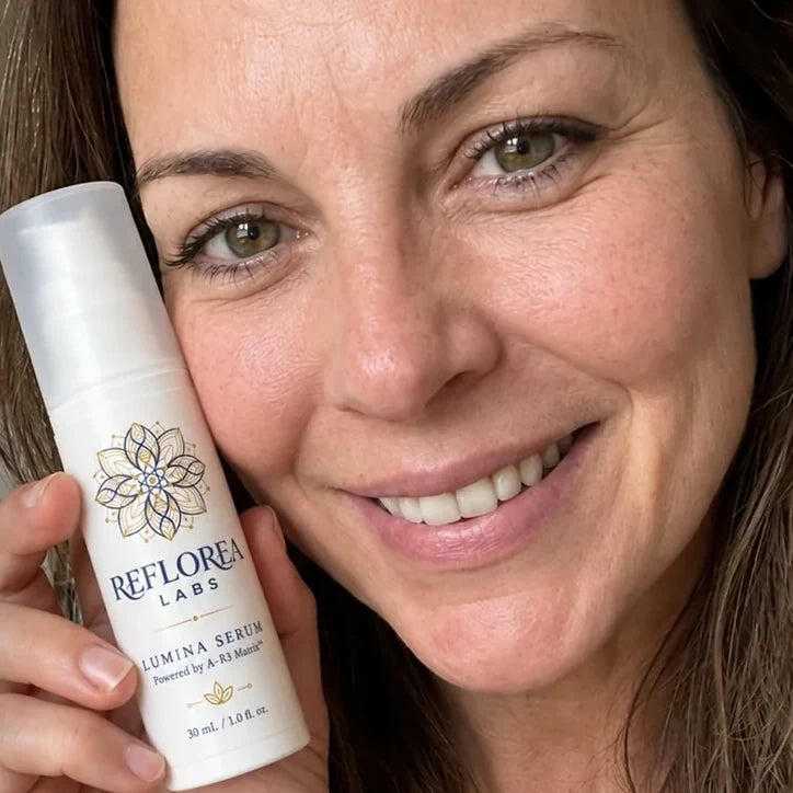 A woman with dark hair holding a bottle of Lumina Serum next to her face