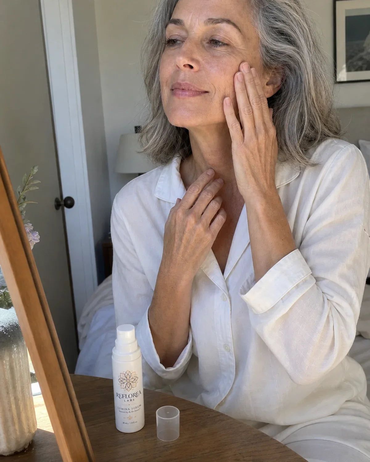 Woman applying serum at her mirror in the evening